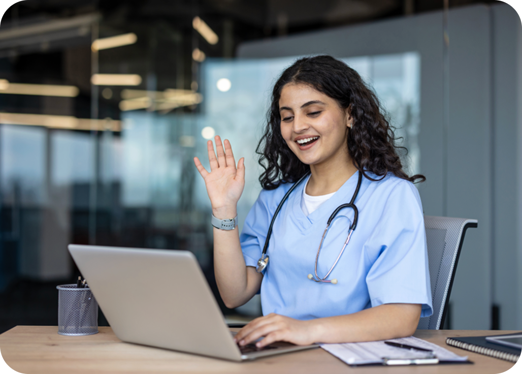A healthcare professional smiling while working on a laptop